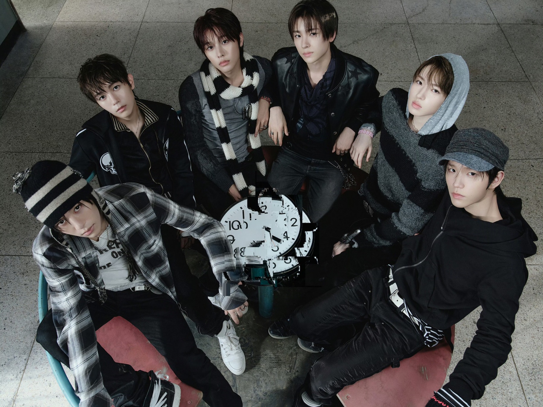 A K-pop boy group gathered around a fragmented clock in a dark industrial setting.