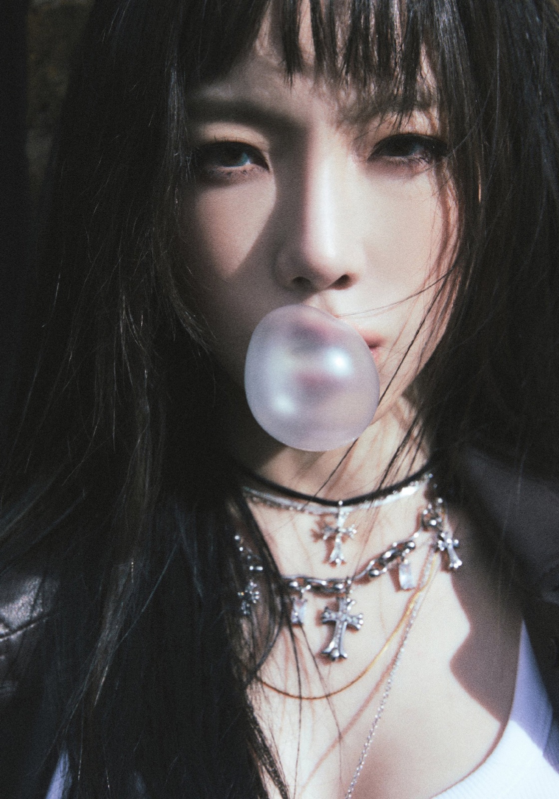 Close portrait of Taeyeon blowing a translucent bubble against a dark background.