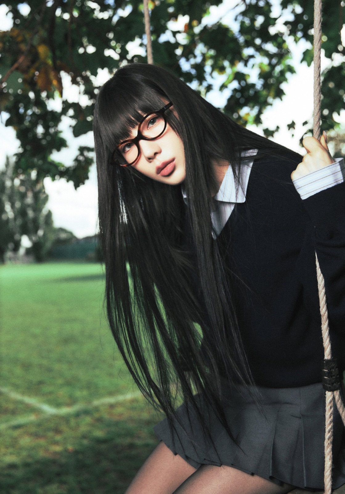 Taeyeon wearing glasses and holding a swing rope in a green outdoor setting.