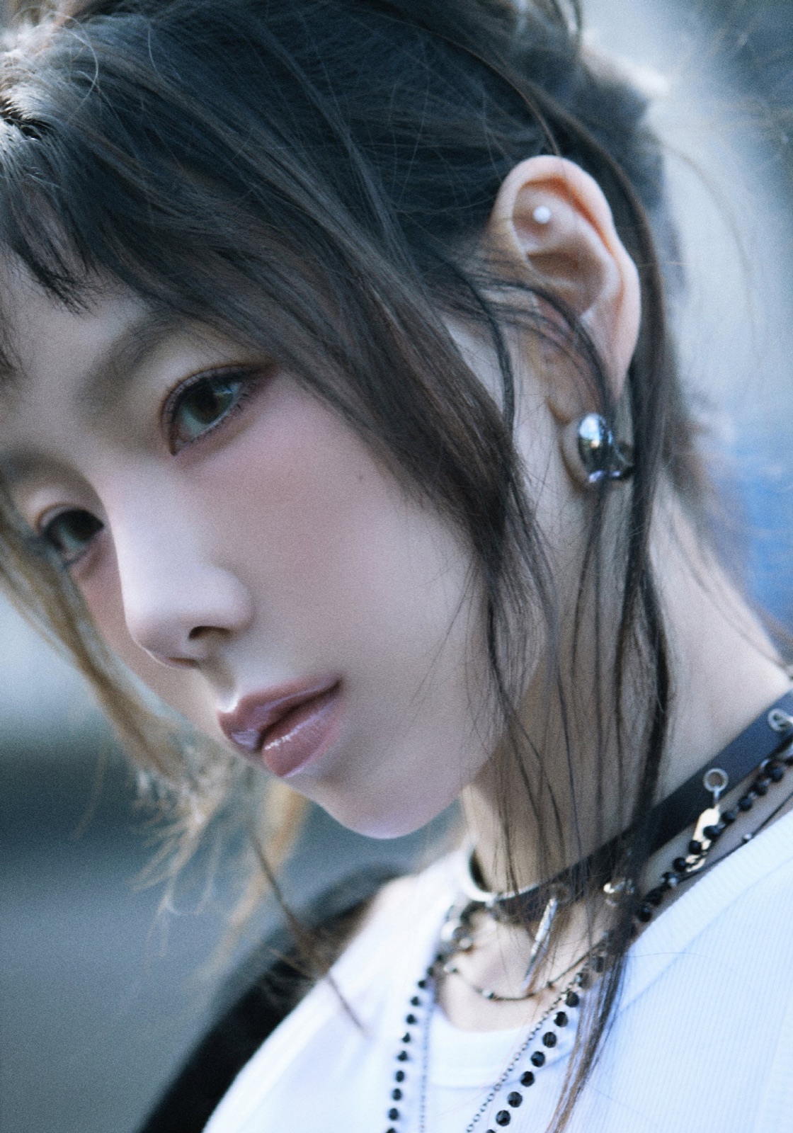 Blue-toned close portrait of Taeyeon looking toward the camera.